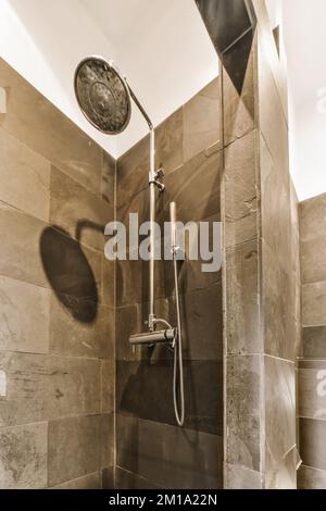 une douche avec une horloge sur le mur à côté et de l'eau venant du robinet dans la douche Banque D'Images