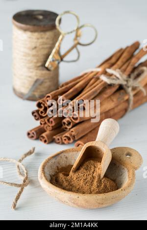 Un petit bol en argile rempli de poudre de cannelle avec des bâtons de cannelle derrière. Banque D'Images