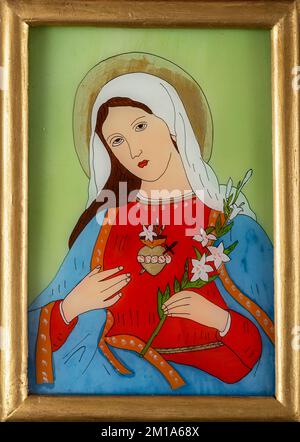 Icône peinte sur un verre à recerse représentant du cœur immaculé de la Vierge Marie tenant une branche de lys blancs. Icône de dévotion catholique romaine dans un or Banque D'Images