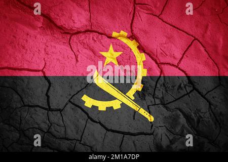 Drapeau de l'Angola. Symbole angolais. Drapeau sur fond de terre sèche fissurée. Concept de drapeau angolais avec sécheresse Banque D'Images