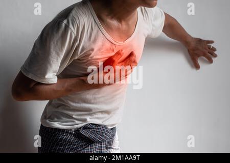 Jeune asiatique souffrant de douleurs thoraciques centrales. La douleur thoracique peut être causée par une crise cardiaque, un infarctus du myocarde ou une ischémie, une myocardite, une pneumonie, s. Banque D'Images