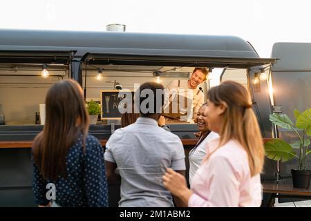 Heureux multiracial personnes achetant le repas de la cuisine de camion de nourriture Banque D'Images