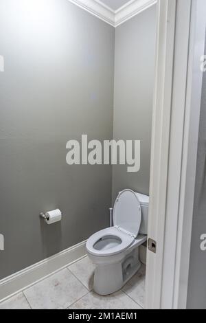 Une petite salle de bains avec des murs gris et des toilettes avec des sols carrelés dans une nouvelle maison de construction Banque D'Images