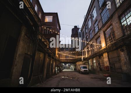 Rue sombre dans une zone industrielle éclairée par de petites lanternes Banque D'Images