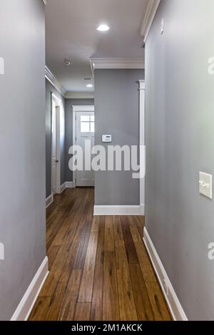 un long couloir avec des murs gris et des planchers de bois franc Banque D'Images