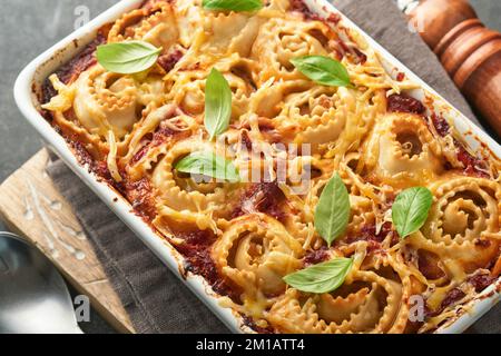 Lasagnes. Pâtes de lasagne faites maison rotolo cuire avec sauce tomate, fromage à la crème et basilic sur une poêle blanche sur fond d'ardoise sombre, de pierre ou de béton. Il Banque D'Images