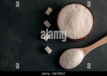 Sucre en cubes et sucre granulé sur fond sombre Banque D'Images