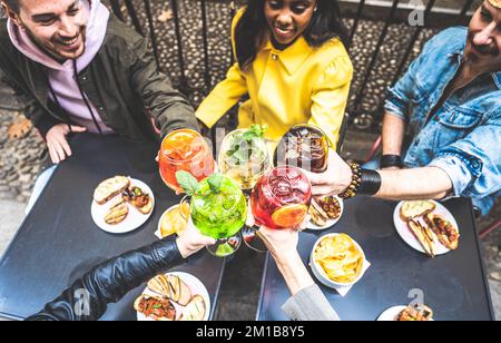Prise de vue en grand angle d'amis multiraciaux en train de déguster un cocktail au bar avec un verre - Groupe de jeunes qui ont la fête en train de boire des cocktails à l'extérieur Banque D'Images