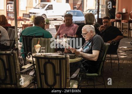 Photo d'un vieil homme lisant un journal de la presse serbe assis sur la terrasse d'un café, à subotica, en Serbie Banque D'Images