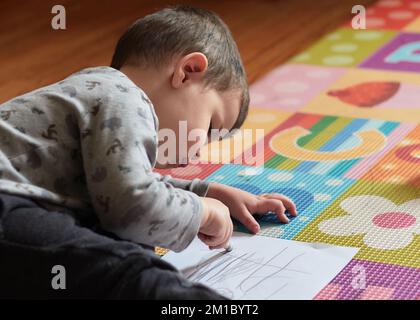 jeune garçon tirant sur un morceau de papier dans sa chambre Banque D'Images