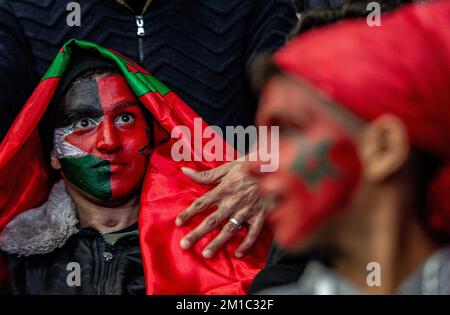 Gaza, Palestine. 10th décembre 2022. Un jeune garçon palestinien avec un visage peint des drapeaux du Maroc et de la Palestine regarde attentivement la diffusion en direct du quart de finale de la coupe du monde de la FIFA entre le Maroc et le Portugal, qui a eu lieu au Qatar, au Saad Sayel Sports Hall à Gaza. (Score final; Maroc 1-0 Portugal) crédit: SOPA Images Limited/Alay Live News Banque D'Images