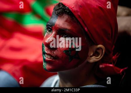 Gaza, Palestine. 10th décembre 2022. Un jeune garçon palestinien avec un visage peint des drapeaux du Maroc et de la Palestine regarde attentivement la diffusion en direct du quart de finale de la coupe du monde de la FIFA entre le Maroc et le Portugal, qui a eu lieu au Qatar, au Saad Sayel Sports Hall à Gaza. (Score final; Maroc 1-0 Portugal) crédit: SOPA Images Limited/Alay Live News Banque D'Images