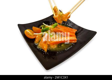 Salade épicée de saumon et de bâtonnets de crabe imitation, nourriture japonaise sur blanc isolé. Banque D'Images