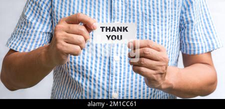 Homme tenant une carte de visite blanche avec des mots, Merci. Banque D'Images