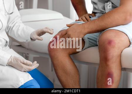 Médecin examinant un homme avec des ecchymoses en clinique Banque D'Images