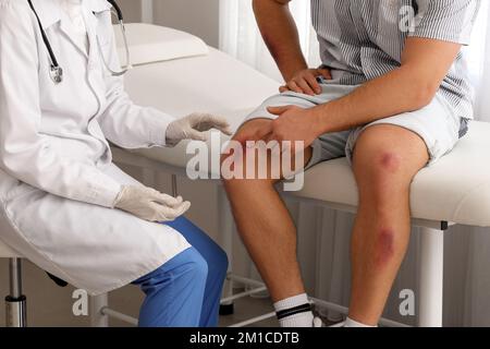 Médecin examinant un homme avec des ecchymoses en clinique Banque D'Images