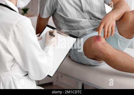 Médecin examinant un homme avec des ecchymoses en clinique Banque D'Images