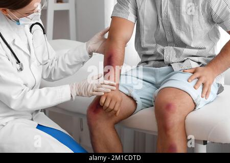 Médecin examinant un homme avec des ecchymoses en clinique Banque D'Images