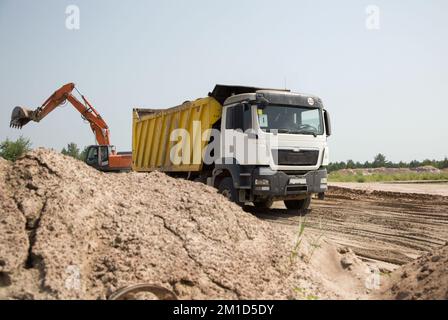 tombereau de chantier avec benne jaune et pelle sur chenilles orange à côté l'une de l'autre lors d'un travail dans une carrière. chargement et transport du sol Banque D'Images