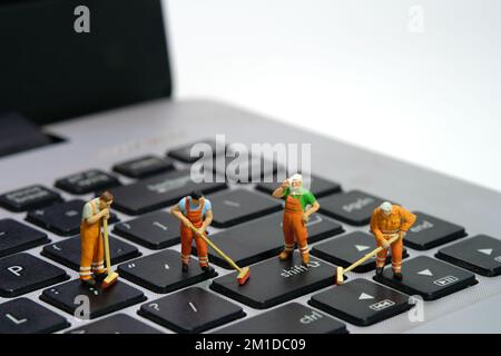 Photographie miniature de personnage de jouet de personnes. Groupe de travailleurs balayeurs nettoyant ordinateur portable clavier à l'aide d'un balai, brosse. Isolé sur fond blanc. Banque D'Images