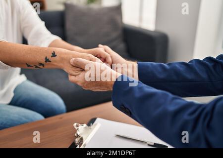 Homme et femme d'âge moyen, pshychologue et consueling de patient tenant les mains au centre de psychologie Banque D'Images