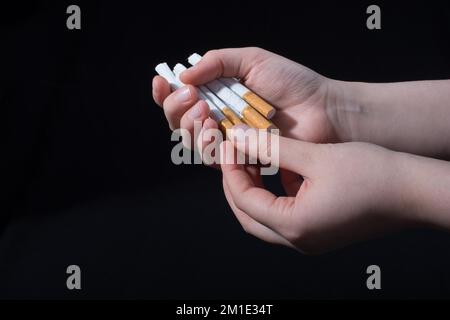 La main est de donner des paquet de cigarettes sur fond noir Banque D'Images