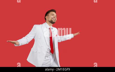 Un homme souriant dansait en costume sur fond rouge Banque D'Images