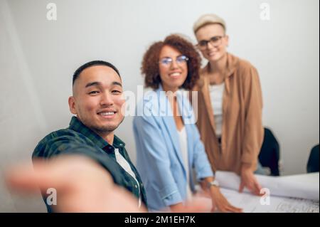 Un dessinateur joyeux se photographiant lui-même et ses collègues lors de la réunion du personnel Banque D'Images
