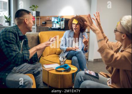 Trois collègues jouent à un jeu de devinettes dans le salon du bureau Banque D'Images