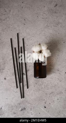Bouteille transparente de diffuseur d'arôme. Parfum pour la maison avec fleurs de coton. Concept tendance, matériaux naturels. Photo verticale sur fond de marbre Banque D'Images
