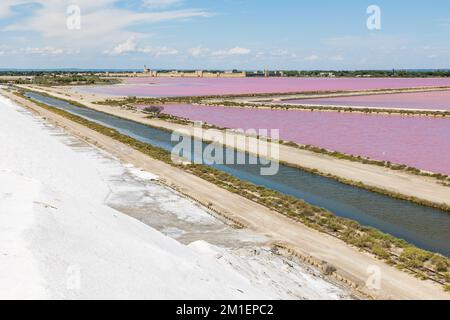 Remparts d'Aigues-mortes devant les marais salants de couleur rose depuis une montagne de sel Banque D'Images