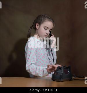 Fille du passé. Portrait dans l'ancien style. une fille compose un numéro sur un ancien téléphone. format carré Banque D'Images