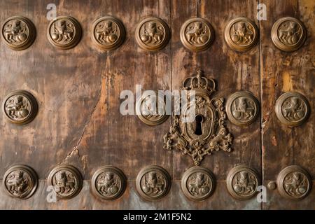 Porte médiévale en bois avec décoration sculptée en bronze avec lions et trou de serrure avec décoration couronne en gros plan. Banque D'Images