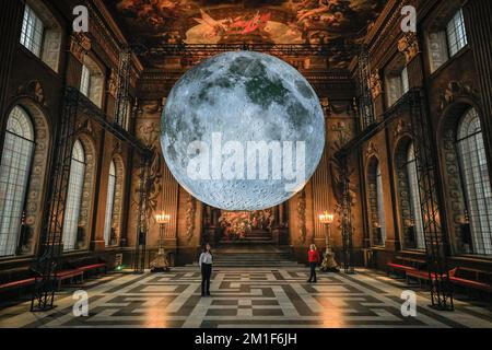 Londres, Royaume-Uni. 12th décembre 2022. Le personnel pose avec l'installation. Le musée de la Lune de l'artiste Luke Jerram, un modèle à l'échelle (1cm = 5km) de la lune, est suspendu dans la salle de peinture baroque, qui fait partie du Old Royal Naval College de Greenwich. La sculpture éclairée à l'intérieur sera exposée jusqu'au 5 février 2023. Credit: Imagetraceur/Alamy Live News Banque D'Images