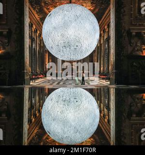 Londres, Royaume-Uni. 12th décembre 2022. Le personnel pose avec l'installation. Le musée de la Lune de l'artiste Luke Jerram, un modèle à l'échelle (1cm = 5km) de la lune, est suspendu dans la salle de peinture baroque, qui fait partie du Old Royal Naval College de Greenwich. La sculpture éclairée à l'intérieur sera exposée jusqu'au 5 février 2023. Credit: Imagetraceur/Alamy Live News Banque D'Images