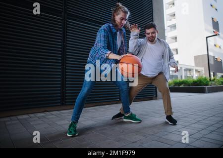 Homme avec le syndrome de Down jouant au basket-ball en plein air avec son ami. Concept d'amitié et d'intégration les personnes handicapées dans la société. Banque D'Images