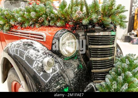 La voiture vintage est décorée de branches de sapin et de décorations de Noël Banque D'Images