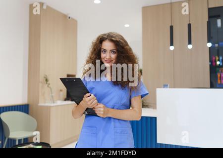 Portrait d'une infirmière dentiste posant à la réception dans une clinique dentaire privée. Banque D'Images