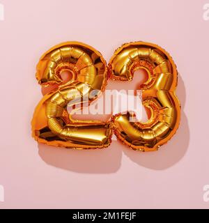 deux ballons dorés en forme de numéro formant le numéro 23 sur fond rose Banque D'Images