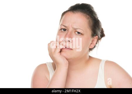 portrait d'une jeune femme chubby nerveuse mordant ses ongles. Banque D'Images