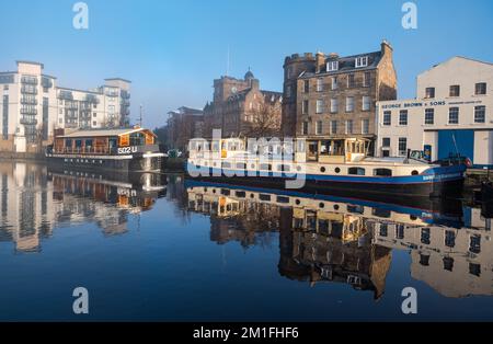 Leith, Édimbourg, Écosse, Royaume-Uni, 12th décembre 2022. Météo au Royaume-Uni : soleil et brouillard. Par un jour amèrement froid, la température ne dépassant pas zéro degré, le soleil brille sur l'eau de Leith créant des reflets colorés dans la rivière avec le brouillard glacial obscurcissant la vue dans la distance et les bateaux à moteur reflétés dans l'eau plate. Crédit : Sally Anderson/Alay Live News Banque D'Images