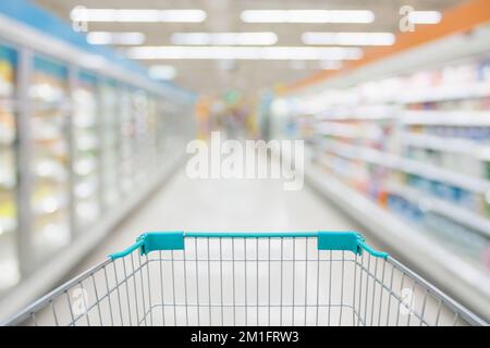 vue du panier avec le résumé de l'allée du supermarché flou produits surgelés et laitiers dans le fond des étagères du réfrigérateur Banque D'Images