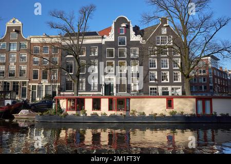 Vue vers l'est sur le canal Prinsengracht montrant une péniche amarrée devant une rangée de maisons traditionnelles d'Amsterdam. Banque D'Images