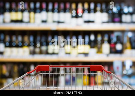 Vue sur le panier avec bouteilles de vin Abstract Blur sur les étagères d'alcool de liqueur dans le supermarché ou magasin de vin arrière-plan Banque D'Images