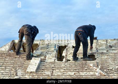 Les constructeurs retirent l'isolation en mousse pulvérisée durcie de l'espace de toit d'une maison privée de banlieue, Shepperton Surrey, Angleterre, Royaume-Uni Banque D'Images