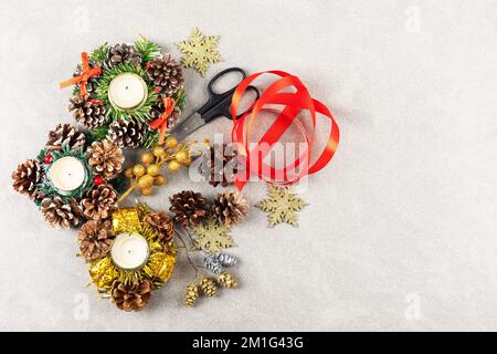 Set pour faire des décorations de Noël sur la table de ciseaux, bijoux, ruban de satin, cônes et bougies sur un fond en bois Banque D'Images