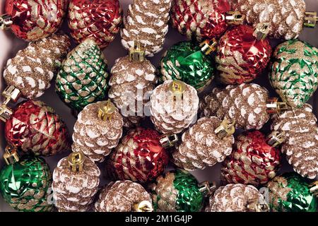 Arrière-plan abstrait des décorations de Noël sous forme de cônes de pin dans les couleurs vert, rouge et or. Carte de vœux de Noël et du nouvel an 2023 Banque D'Images