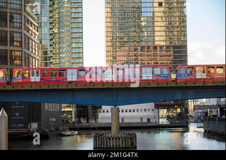 LONDRES - 4 novembre 2020: Docklands Light Railway le train DLR traverse le pont au-dessus de l'eau à Canary Wharf avec des immeubles de bureaux modernes en arrière-plan Banque D'Images