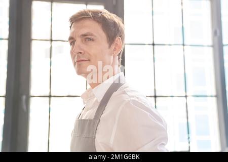 Portrait d'un jeune homme regardant soigneusement par la fenêtre. Dans un bâtiment de café avec de l'espace pour copier. Photo de haute qualité Banque D'Images