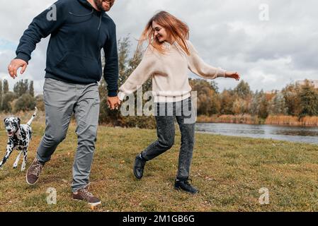 Un jeune couple s'amuse avec un chien dalmate en plein air. Banque D'Images